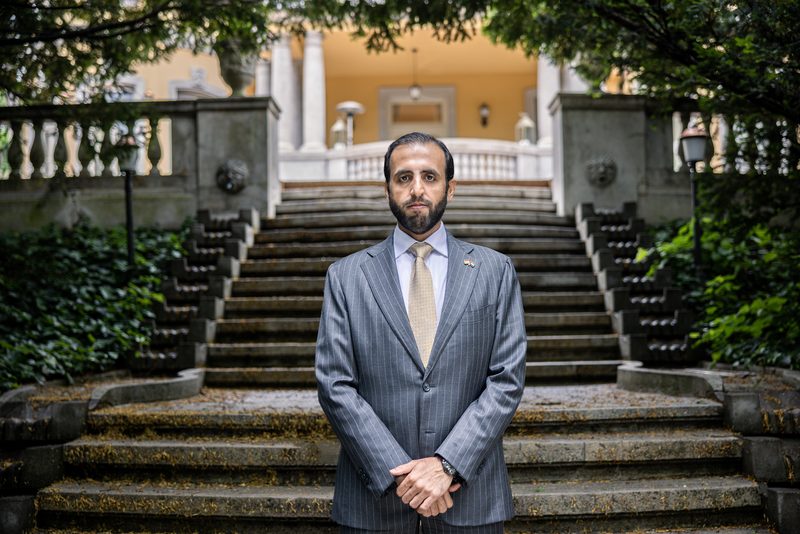 Saud H. Alshamsi szürke csíkos öltönyben áll egy kerti kőlépcső alján, egy oszlopos épület előtt.